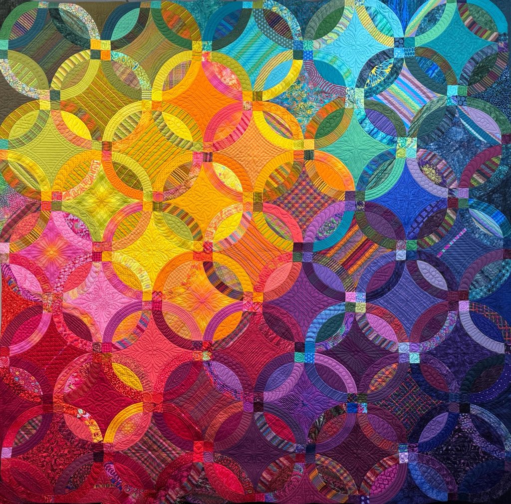Northwest Suburban Quilters Guild Opportunity Raffle Quilt for 2025 features deep saturated rainbow colors and the design is a Double Wedding Ring 98x98